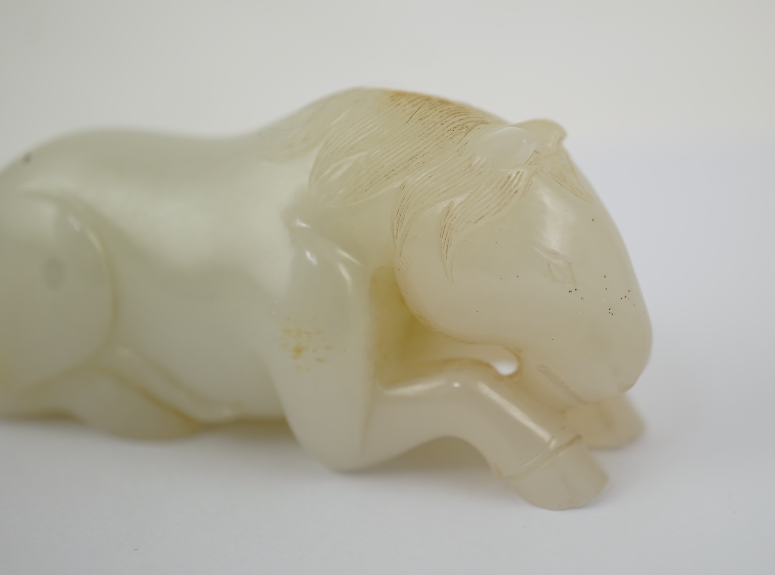 A Chinese white jade figure of a recumbent horse